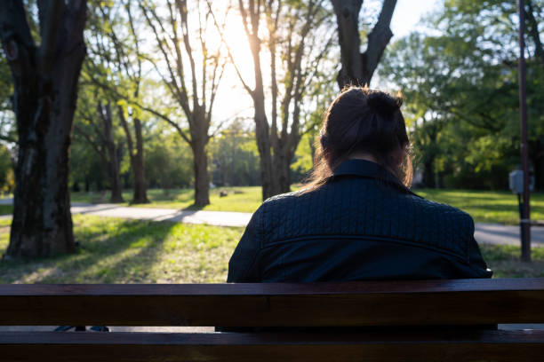 A mature woman sitting on a park bench.