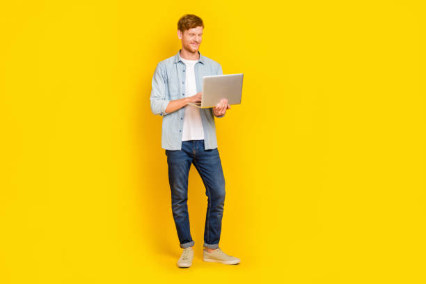 istock Photo of pretty attractive guy dressed denim shirt typing modern device empty space isolated yellow color background 2186641142