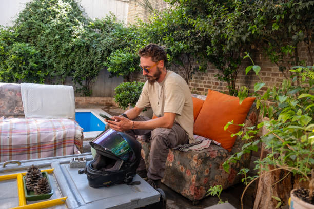 Motorcyclist relaxing in the garden, browsing smartphone