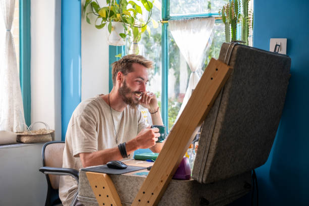 Young man working remotely from home office, enjoying a cup of coffee