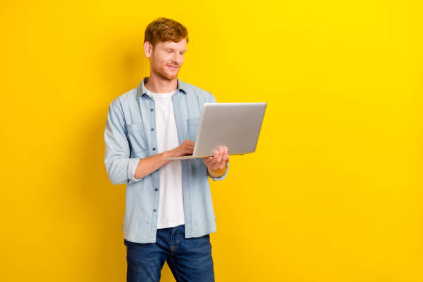istock Photo portrait of charming young guy hold laptop coding test use new software wear stylish jeans outfit isolated on yellow color background 2186651754