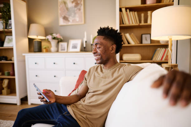 istock Relaxed Black Man Using Smartphone in Cozy Living Room Setting 2186652437
