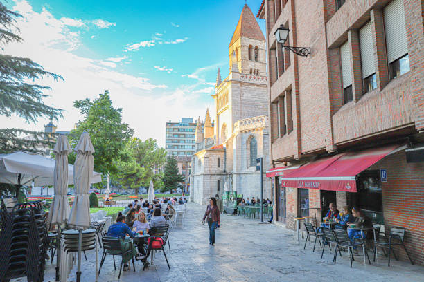 October, 2024. Valladolid, Spain. Some random people enjoying the afternoon, church tower in the background.