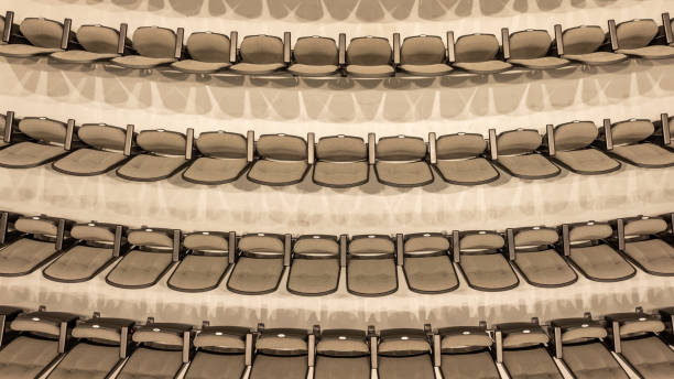 Overhead image of empty tan / gray theater, auditorium seats, chairs.