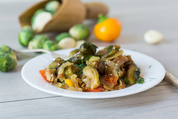 istock Brussel sprouts cooked with vegetables and spices, on a wooden table 2186658446