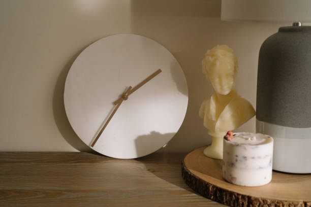 istock minimalist decor for a living room. A minimalistic sideboard with white marble clock, aesthetic candles and a table lamp. Minimal aesthetic and simplicity concept 2186664577