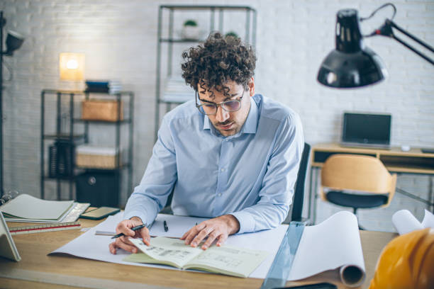 istock Focused architect reviewing documents at home office desk 2186666287
