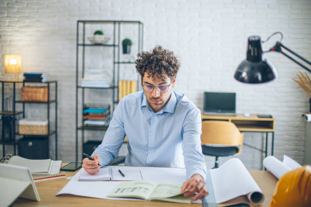 istock Architect concentrating on paperwork, managing projects and working remotely in a bright home office 2186667049