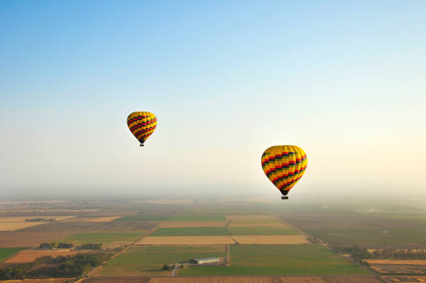 istock Two Hot Air Balloons Flying Over Farms 2186674625