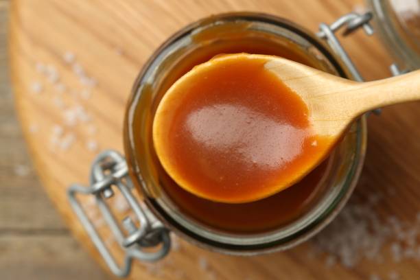 istock Jar and spoon with tasty salted caramel on table, top view 2186678946