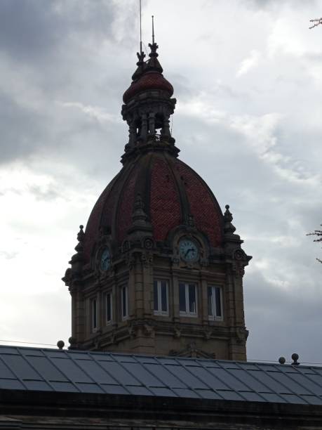 istock Building with a clock and a red roof tower over the cloudy sky 2186680128