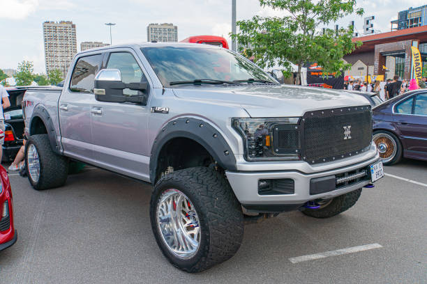 A large, customized pickup truck is positioned at an angle to showcase its front and side, featuring oversized wheels and tires with distinctive rims Kyiv, Ukraine 06-06-2024