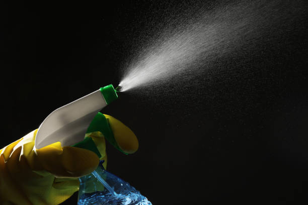 istock Woman spraying liquid from bottle on black background, closeup 2186682143