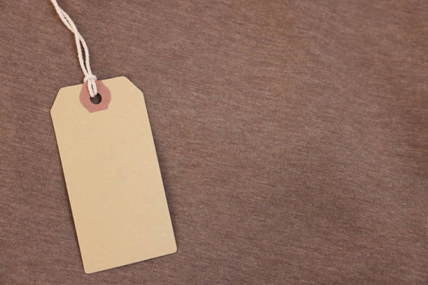 istock Cardboard tag on brown garment, top view. Space for text 2186682235