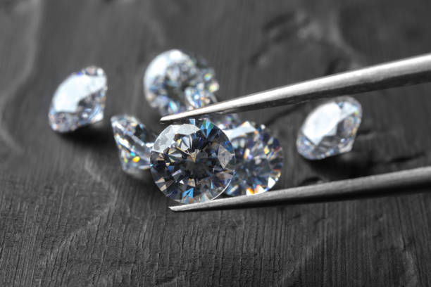 istock Tweezers with beautiful shiny diamond above dark gray table, closeup 2186682280