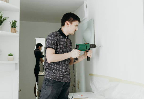istock A young man drills a hole in the wall. 2186683446