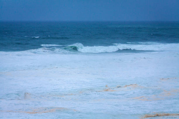 istock A vast, powerful ocean with rolling waves and white foam stretches under a soft, misty blue sky, creating a serene yet dynamic seascape 2186683680
