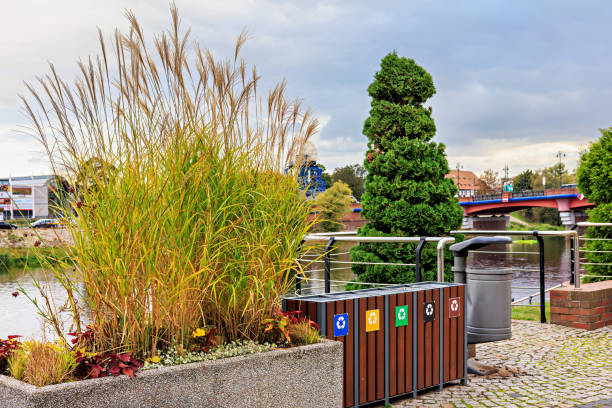 Stylish containers for waste segregation on the city pier with a bridge. Caring for the environment.