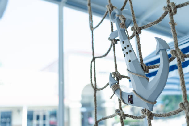 Decorative White Anchor Hanging on Nautical Rope Netting, Coastal Decor, Maritime Theme and Seaside Aesthetic in Bright Setting. Travel Summer Beach.