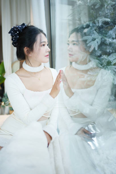 Asian woman looking at herself on the glass window