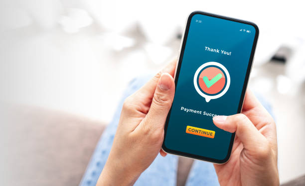 istock Female hand holding a mobile phone showing successful payment message application with check mark. Business, Digital online payments and technology concepts 2186719576