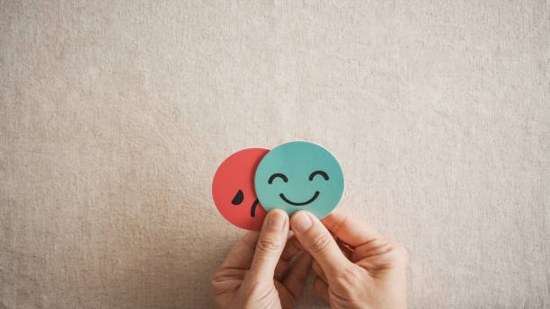 istock Hands holding sad face hiding behind happy face, bipolar and depression, mental health, split personality, mood change concept 2186721430