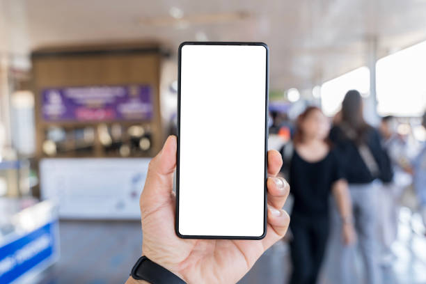 istock Man's hand holding mobile phone with white empty screen in front of blurry subway 2186722908