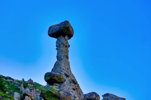 A stunning collection of unique stone mushrooms crafted by nature, nestled in a picturesque mountain landscape. This rare phenomenon showcases striking formations against a clear sky.