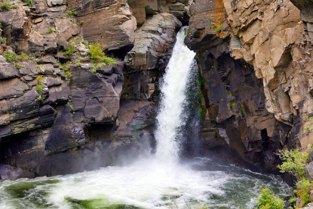 This stunning image captures a small waterfall gracefully flowing from a crevice in the mountain. The surrounding nature adds beauty and tranquility to this serene landscape.