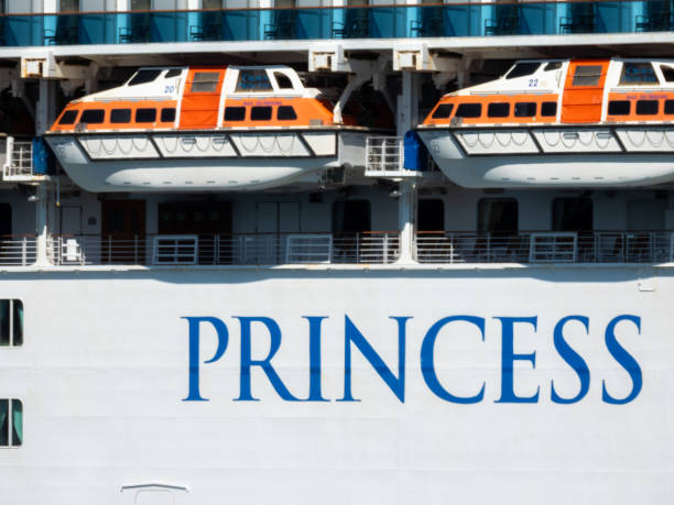 The hull, lifeboats, decks, part of the ships' name and cabin balconies of the Crown Princess cruise ship berthed at the overseas passenger terminal in Circular Quay, Sydney Harbour. This image was taken from a passenger ferry travelling between Manly and Circular Quay on a sunny, hot and windy afternoon on 23 November 2024.