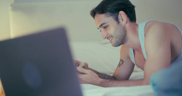 istock Man relaxing in bed with laptop and smartphone. 2186727755