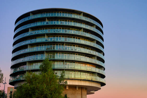 Modern round building with glass facade. Modern residential building with curved design at sunset. Detail of contemporary architecture