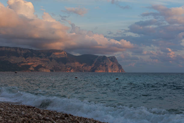 Sea sand evening. Blue post-sunset hour on the seashore. The last rays of the sun are reflected in the waves. Glowing sea foam rolls onto the beach. The concept of summer vacation, relaxation, privacy