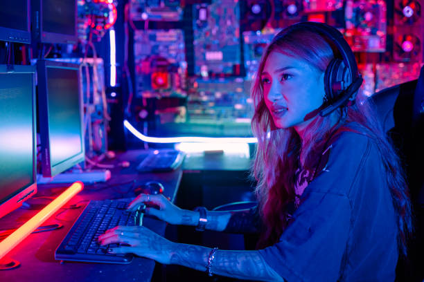 istock Woman hacker sitting in front of a computer typing on keyboard hacking servers in neon light, Female hacker breaks into data center, Gamer woman streaming game online 2186733782