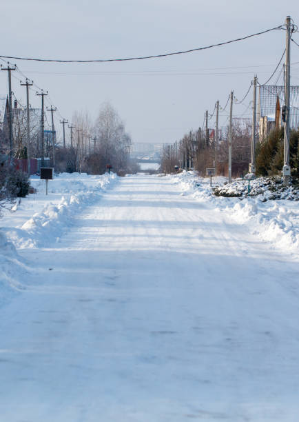 Slippery winter road. Winter evening village. Winter road through a snow-covered village, severe frost, snow haze. Perm Region, the hinterland of Russia.