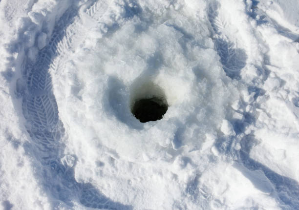 A large hole in the snow with a tire track around it