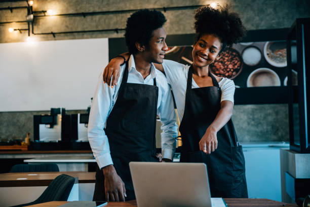 istock Cafe owners a black barista and owner plan supply orders on laptop. Discussing work schedule menu teamwork in coffee shop aiming for business success financial planning. 2186734051