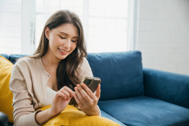 istock In a relaxed home setting a woman on a sofa happily talks on her phone typing messages. Engaged in successful communication and technology she embodies relaxation. The woman is relaxing. 2186734094