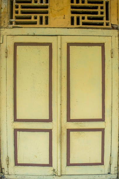 An old, weathered yellow wooden window with peeling paint against a rustic wall, perfect for themes of vintage charm and urban decay