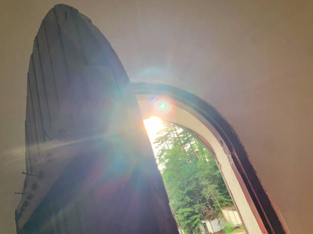 A ray of sunlight streams through an open arched doorway, casting a warm glow on the interior and hinting at the lush greenery beyond.