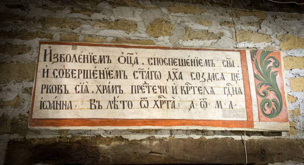 A historical inscription in Cyrillic script is displayed on an old stone wall