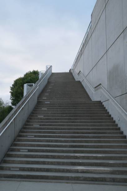istock Long, steep concrete staircase stretches upward, seemingly towards the sky, with no visible end 2186738945