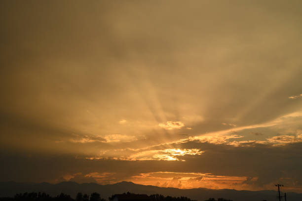 Warm hues fill the sky as the sun sets behind the mountains, casting beautiful light and shadow across the landscape.