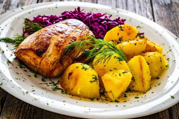 istock Fried pork loin with boiled potatoes and red cabbage on wooden table 2186739643
