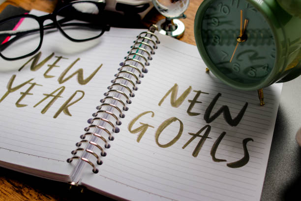 Notebook with New Year, New Goals and Clock