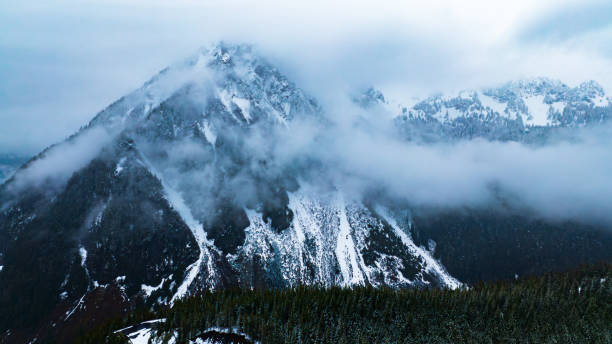 Mountain American nature with clouds. Clouds over forest of Mount Rainier park..