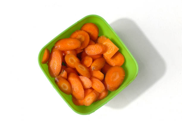 istock Carrot slices in a green plastic bowl, isolated on a white background 2186748300