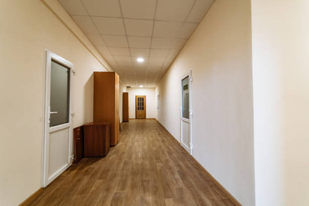 istock Long hallway with wooden flooring and office doors in a building. A well-lit hallway features wooden flooring and multiple doors leading to offices 2186750496