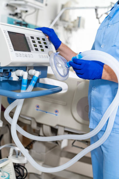 istock A man in a blue uniform is holding a tube connected to a machine. The machine is a ventilator 2186750720
