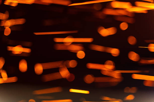 Vibrant sparks and glowing particles captured in a dark setting. Sparks and glowing particles dance through the air, creating a mesmerizing effect in a dark environment